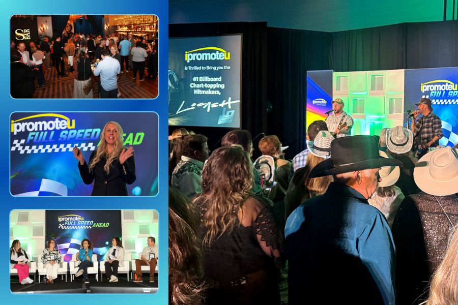 Crowd at an iPromoteU conference listening to a panel on stage with branded screens in the background.