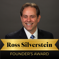 12_Founders_Award Smiling man in a dark suit with a gold ribbon banner reading 'Founder’s Award'.
